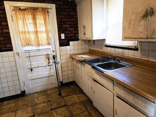 kitchen featuring tile walls and a sink