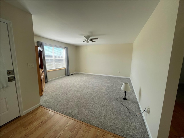 empty room with a ceiling fan, carpet, baseboards, and wood finished floors