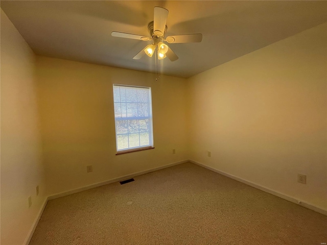 empty room featuring visible vents, light colored carpet, a ceiling fan, and baseboards