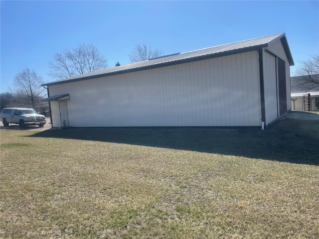 view of side of home featuring an outbuilding, a yard, and metal roof