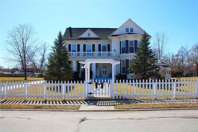 view of front of house with a balcony and a fenced front yard