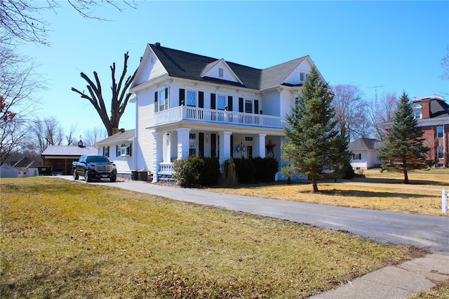 view of front facade featuring cooling unit, driveway, a balcony, and a front lawn