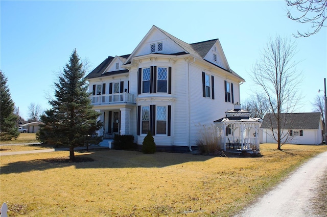 view of front facade with a gazebo, a front yard, and a balcony