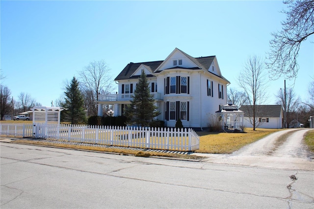 victorian house featuring a fenced front yard and a balcony