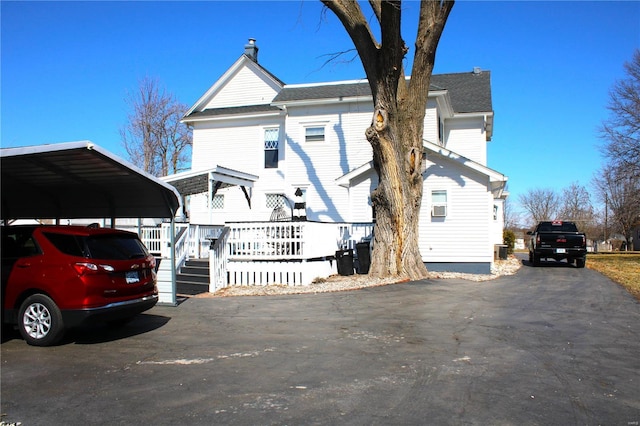 view of front of property with a detached carport, a deck, and driveway