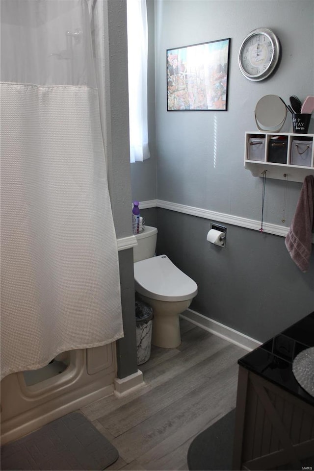 full bath with toilet, baseboards, and wood finished floors