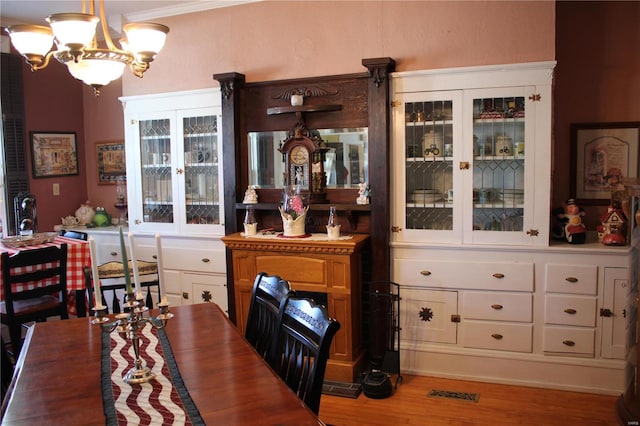 dining area featuring a chandelier, visible vents, wood finished floors, and ornamental molding