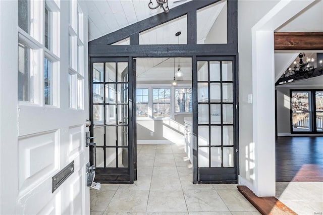 tiled entrance foyer with a healthy amount of sunlight, vaulted ceiling with beams, and baseboards