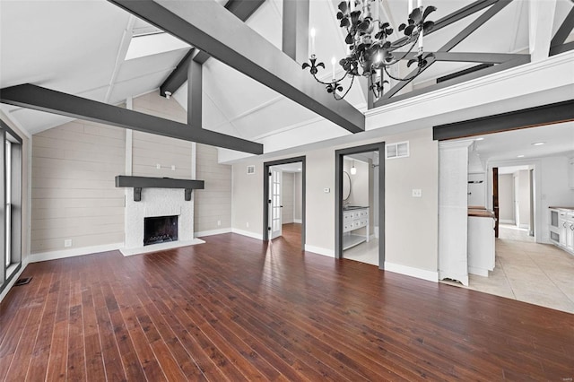 unfurnished living room featuring visible vents, an inviting chandelier, beam ceiling, light wood-style floors, and a large fireplace