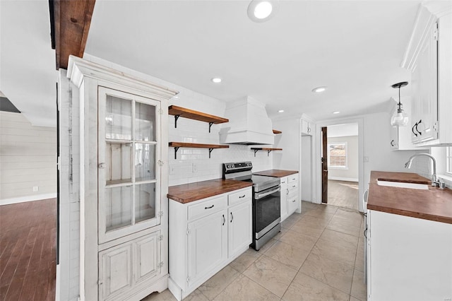 kitchen featuring a sink, custom range hood, electric stove, tasteful backsplash, and butcher block counters