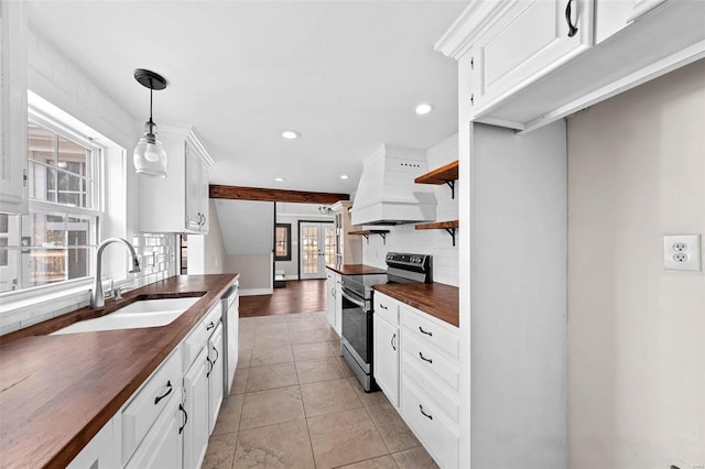 kitchen with a sink, stainless steel electric range oven, wooden counters, custom exhaust hood, and dishwasher