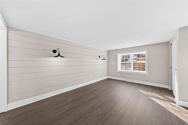 interior space with visible vents, baseboards, dark wood-style floors, and wood walls