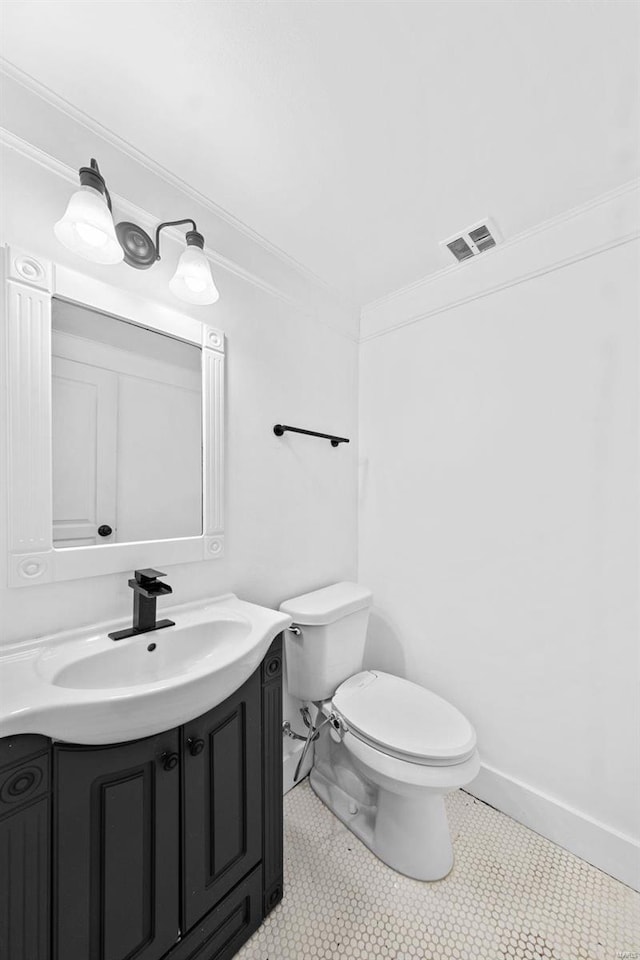 half bathroom with vanity, baseboards, visible vents, crown molding, and toilet