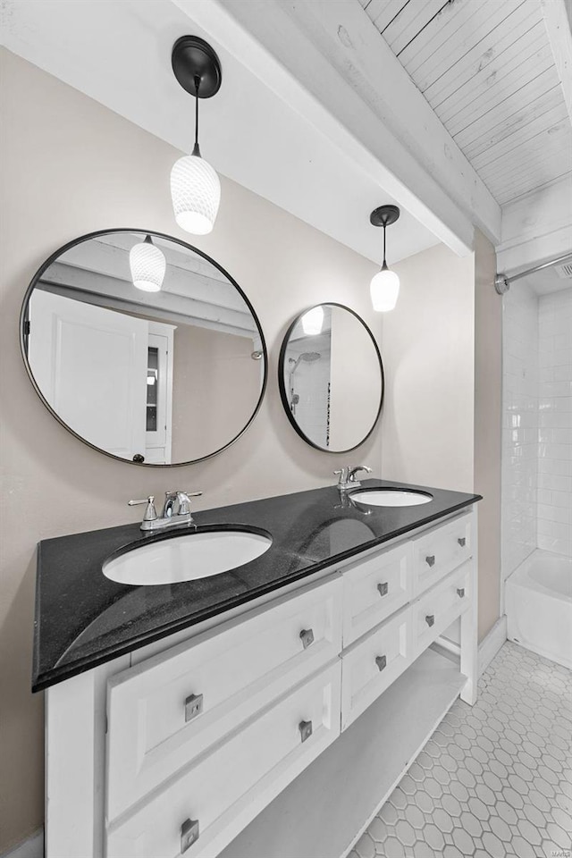 full bath with beam ceiling, double vanity, and a sink