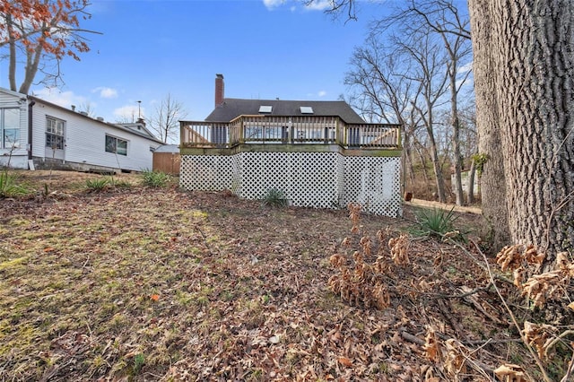 rear view of property featuring crawl space, a chimney, and a wooden deck