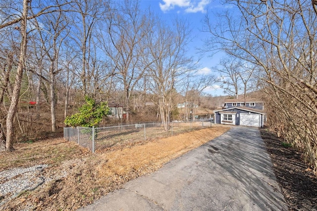 view of yard with an attached garage, fence, and driveway