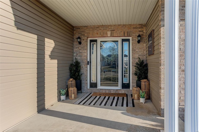 property entrance featuring a porch and brick siding