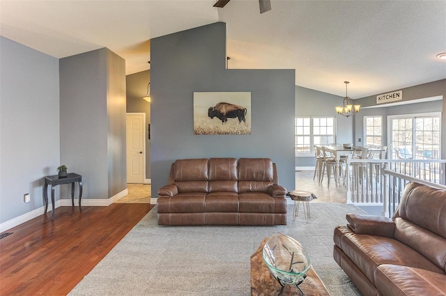 living room with lofted ceiling, wood finished floors, baseboards, and a chandelier