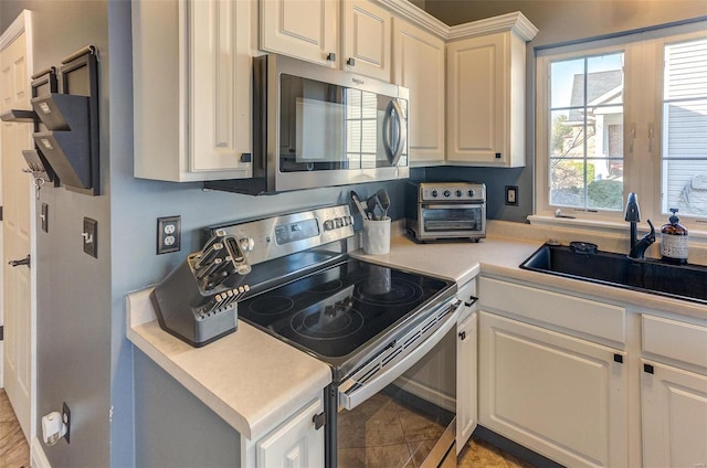 kitchen featuring white cabinetry, light countertops, appliances with stainless steel finishes, and a sink