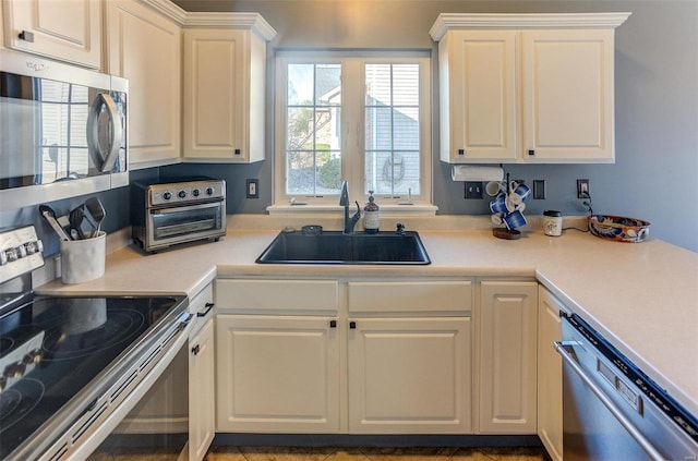 kitchen featuring a sink, stainless steel appliances, light countertops, and white cabinetry