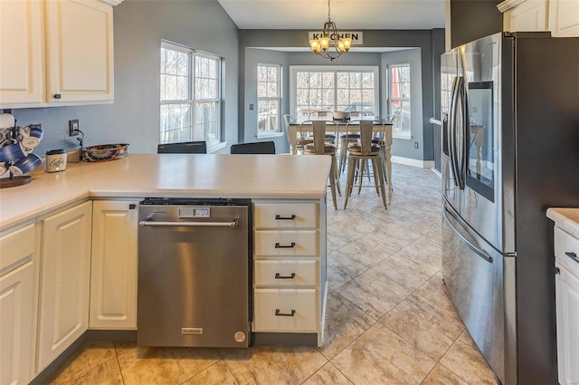 kitchen featuring a notable chandelier, decorative light fixtures, appliances with stainless steel finishes, a peninsula, and light countertops