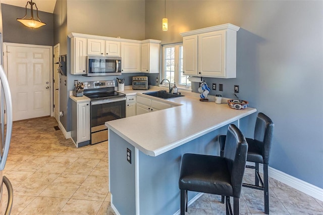 kitchen with a breakfast bar area, a peninsula, white cabinets, stainless steel appliances, and a sink