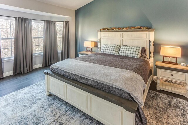 bedroom featuring lofted ceiling, wood finished floors, and baseboards