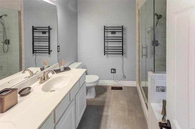 bathroom with vanity, radiator, baseboards, a shower stall, and toilet