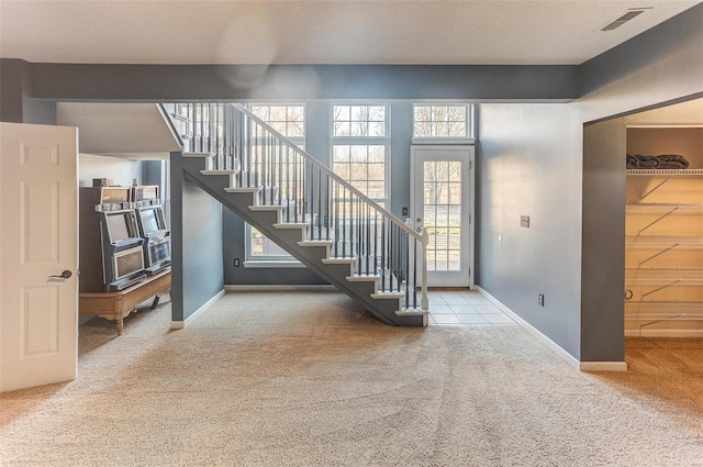 carpeted entrance foyer with visible vents, stairs, and baseboards