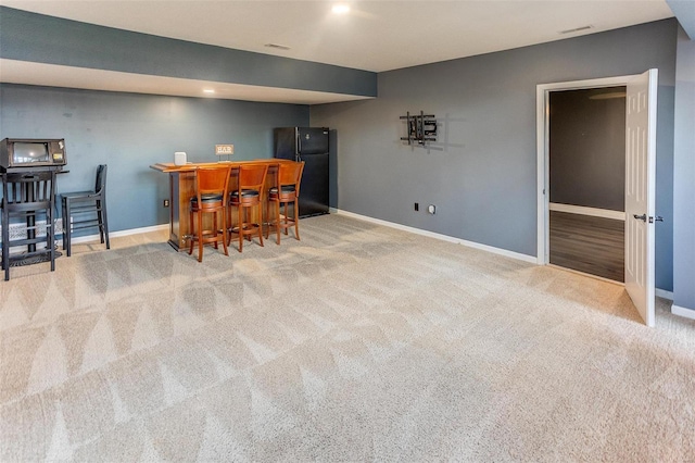 bar featuring carpet, visible vents, baseboards, freestanding refrigerator, and a dry bar