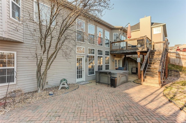 rear view of property featuring a patio, stairway, a wooden deck, a hot tub, and decorative driveway