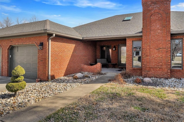 view of front of house with brick siding, a chimney, an attached garage, and a shingled roof