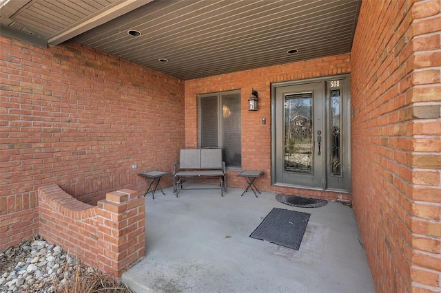 doorway to property featuring a patio and brick siding