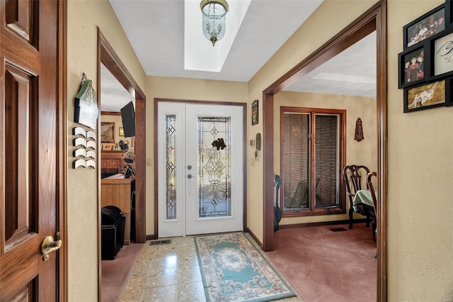 carpeted foyer entrance with visible vents and baseboards