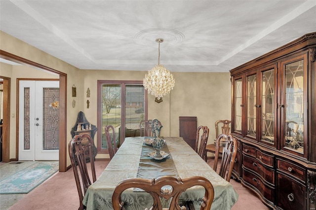 dining area featuring light carpet, a notable chandelier, and a tray ceiling