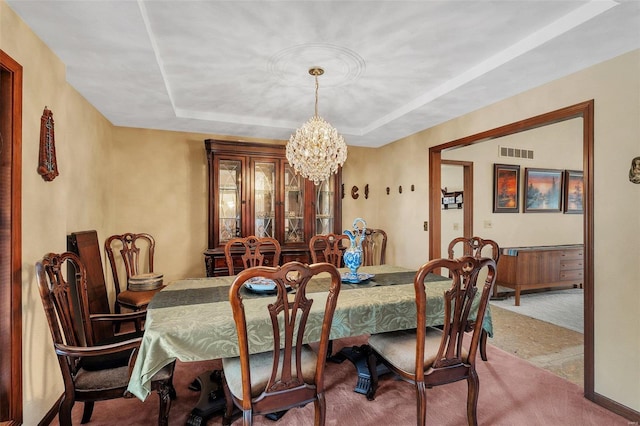 carpeted dining space featuring visible vents, a raised ceiling, and an inviting chandelier