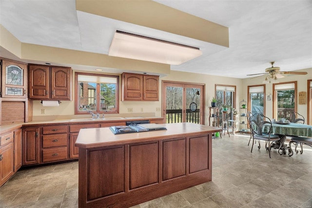 kitchen featuring brown cabinets, a kitchen island, light countertops, and a sink