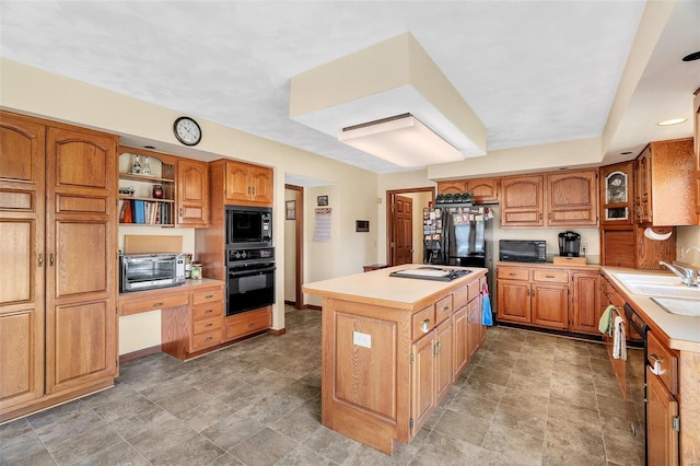 kitchen featuring a kitchen island, a toaster, a sink, black appliances, and light countertops