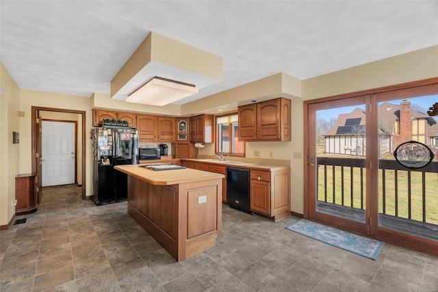 kitchen featuring a kitchen island, black appliances, light countertops, and baseboards