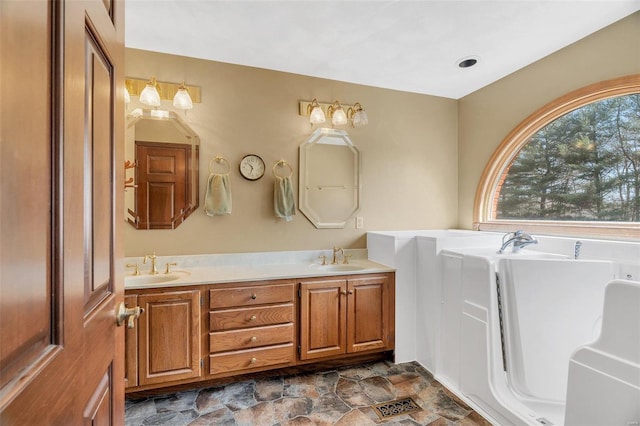 full bath with a sink, a bath, double vanity, and stone finish floor