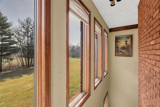 entryway with a wealth of natural light, brick wall, and a textured ceiling