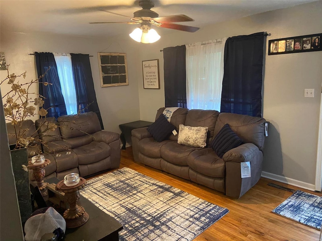 living area with ceiling fan, baseboards, and wood finished floors