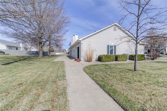 view of property exterior featuring a lawn, a chimney, and fence