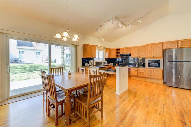 dining room featuring rail lighting, light wood-style floors, a chandelier, and high vaulted ceiling