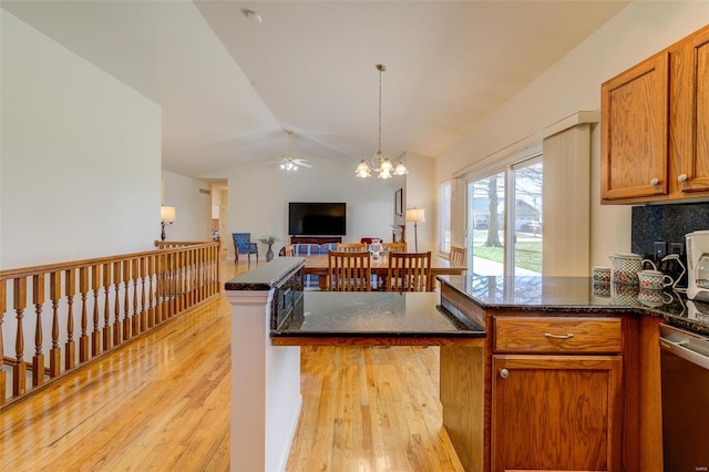 kitchen featuring open floor plan, lofted ceiling, light wood-style flooring, a peninsula, and brown cabinetry