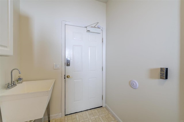 clothes washing area featuring baseboards and a sink