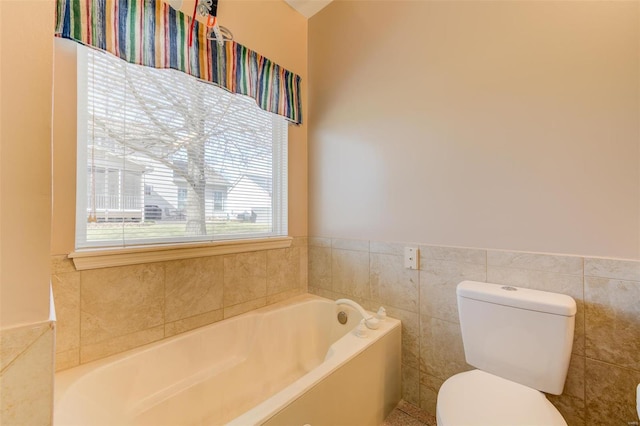 bathroom featuring a wainscoted wall, toilet, tile walls, and a garden tub