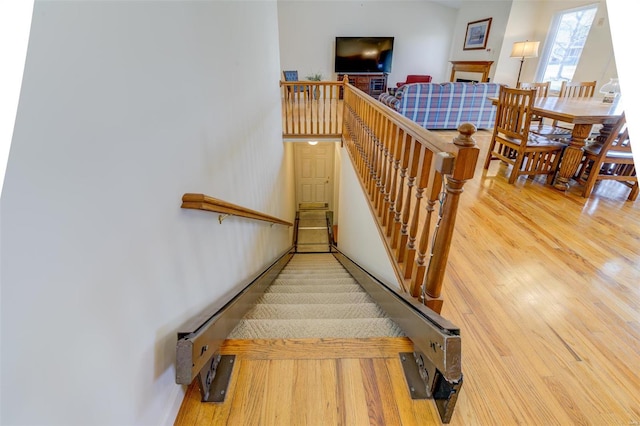 stairs featuring a fireplace and wood finished floors