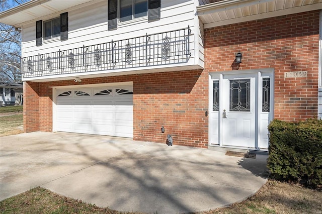 entrance to property featuring concrete driveway, brick siding, and a garage