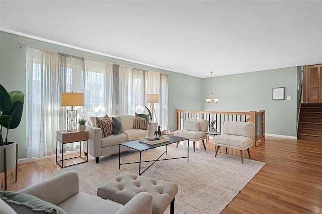 living room featuring stairs, wood finished floors, baseboards, and a chandelier